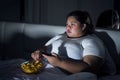 Obese woman eating popcorn in bed