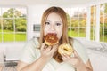 Obese woman eats two donuts at home Royalty Free Stock Photo
