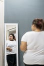 Obese woman looking at her fat belly in the mirror