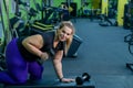 An obese woman is training with dumbbells on a bench in the gym. The fat blonde is losing weight with the help of
