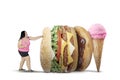 Obese woman fights with unhealthy foods on studio Royalty Free Stock Photo