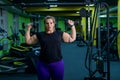 An obese woman is working on losing weight. Fat blondes train biceps with a dumbbell in the trainer room. A lot of Royalty Free Stock Photo