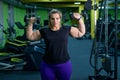 An obese woman is working on losing weight. Fat blondes train biceps with a dumbbell in the trainer room. A lot of Royalty Free Stock Photo