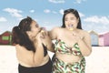Obese women eat ice cream at shore