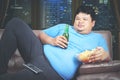 Obesity man eating and drinking while watching TV Royalty Free Stock Photo