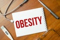 OBESITY text on white paper on the white background. stethoscope