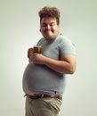 Obesity, weight gain and lager for man in studio with drink for unhealthy habit, plus size and joke. Overweight person