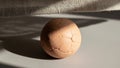 Object with a cracked orange brown surface rests on a light gray Royalty Free Stock Photo