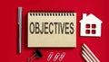 OBJECTIVES text written on a notebook with pencils and office tools and model wooden house Royalty Free Stock Photo