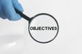 Objectives word inscription through magnifying glass in hand in gloves