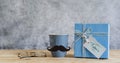 Objects on the table of Happy Fathers day holiday background concept.Greeting card with gift box and Black mustache on grey