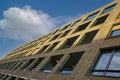 Oblique view on modern brown brick stone facade with many windows against blue sky with cumulus cloud - Maastricht, Netherlands