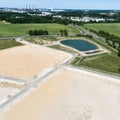 Obliquely taken aerial view of a construction site for a new development with a large filled rain retention basin