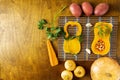 Oblong pumpkin in two parts with other vegetables on a bamboo napkin and on an oak wood background