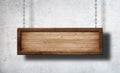 Oblong wooden sign hanging on chains with concrete wall background