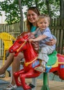 2010.08.15, Obninsk, Russia. A mother and a little boy spinning on a carousel horse and laughing.