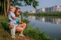 2010.08.15, Obninsk, Russia. Mother and son sitting on the grass at the river bank.