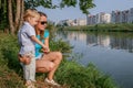 2010.08.15, Obninsk, Russia. Mother and son sitting on the grass at the river bank.