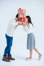 obscured view of couple kissing behind stack of wrapped christmas gifts