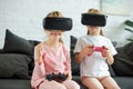 obscured view of kids in virtual reality headsets playing video game on sofa Royalty Free Stock Photo