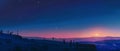 Observers equipped with telescopes take in the starry sky as the day's last light fades on a snowy mountain range.