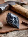 Obsidian rock and hammer on a leather surface. Royalty Free Stock Photo