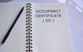 Occupancy certificate text written on a notepad with a pen