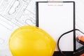 Occupational Safety and Health, clipboard text mockup and construction protective clothing on background of architectural drawings