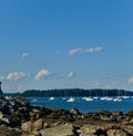 Sailboats sitting on ocean bay between an island and a rocky shore Royalty Free Stock Photo