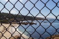 Ocean behind metal mesh fence . Restraint of liberty Royalty Free Stock Photo