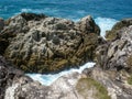 Ocean blowhole in between eroded rocks and cliffs with blue sea in the background. Royalty Free Stock Photo