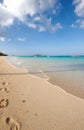 Ocean, boat and blue sky for footprints, sand and rocks in shore for peace and tranquility. Seaside, waves and summer Royalty Free Stock Photo