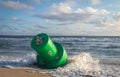 Ocean buoy washed up on a beach has waves crashing on it