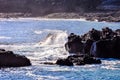 The ocean is calm and the rocks are scattered throughout the water