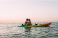 Ocean coast, a loving couple sitting on a kayak in the water and kissing