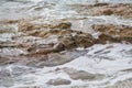 Ocean in Cornwall in the daytime, waves lapping on to the stony shore