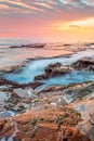 Ocean flowing into coastal channels eroded into rock and a stunning sunrise