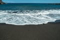 Ocean foam covering wonderful black sand beach of Tenerife island