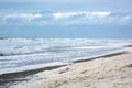 Ocean foam on sand beach during mild sea storm with waves in background in Europe Royalty Free Stock Photo