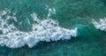 Ocean foamy waves approaching rocky shore. Top view