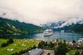 Ocean liner in village harbor. Ship in norwegian fjord on cloudy sky. Travel destination, tourism. Adventure, discovery Royalty Free Stock Photo