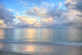 Ocean rolls in under puffy clouds on North Naples Beach at sunrise Royalty Free Stock Photo