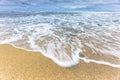 Ocean sea water rushing in to sandy beach shore on a cloudy blue sky. Royalty Free Stock Photo