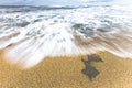 Ocean sea water rushing in to sandy beach shore on a cloudy blue sky. Royalty Free Stock Photo