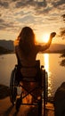 Ocean sunset backdrop accentuates female wheelchair users silhouette, arms outstretched