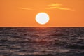 Ocean sunset. Big white sun on dramatic bright sky background, soft evening cloud over sea dark water Royalty Free Stock Photo