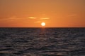 Ocean sunset. Big white sun on dramatic bright sky background, soft evening cloud over sea dark water Royalty Free Stock Photo