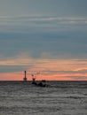 ocean sunset with fishing boat and small lighthouse Royalty Free Stock Photo