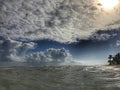 The ocean sunset. The setting sun highlights some cumulus clouds with golden rays