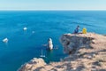 Ocean view and floating yacht in water. Lady enjoying seascape on cliff. Remote office and travel time idea, copy space